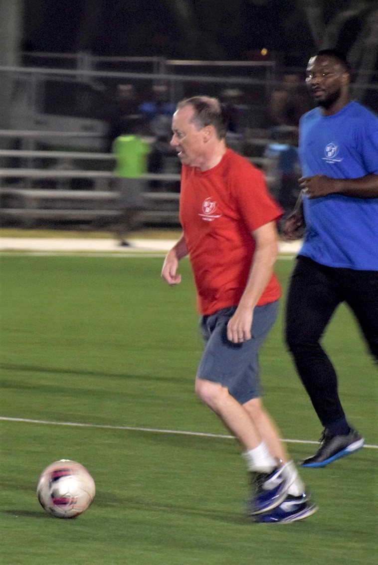 Reds team member H.E the Governor tackles the ball, pictured with Samuel Rose