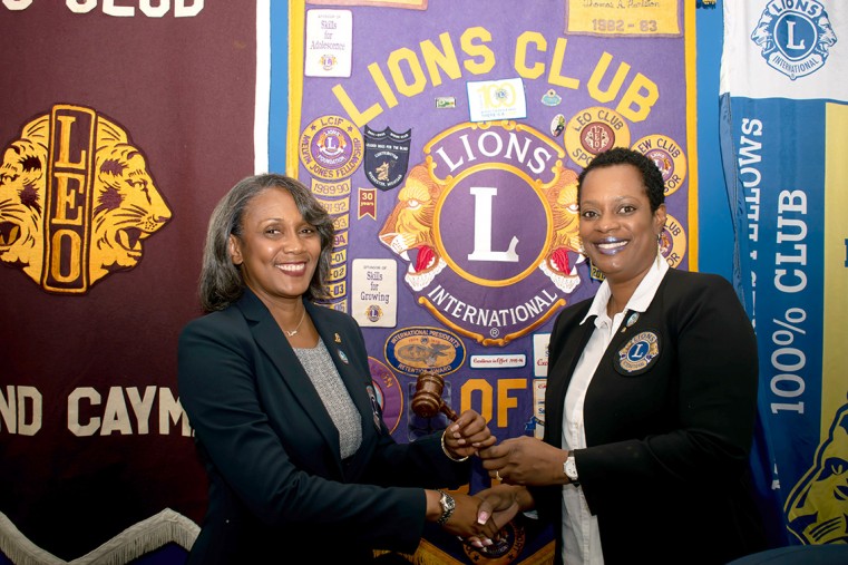 Immediate Past President Cordella Chollette passes the gavel to new Lions Club of Grand Cayman President Carmin Godfrey