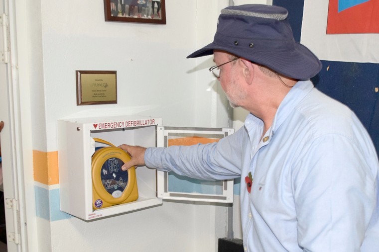 Cayman Islands Sailing Club Commodore, Allan Rofferty, places the new AED in a special case, so that everyone at the club will know where it is in the case of an emergency