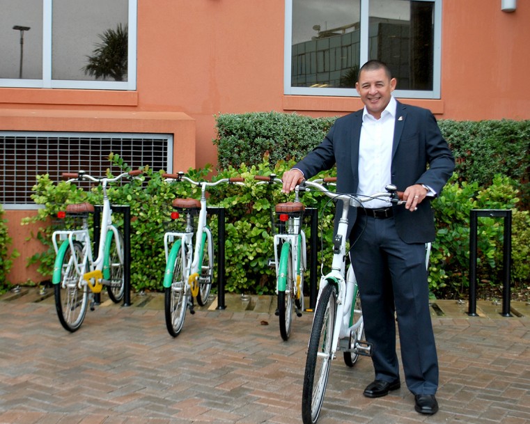 The Honorable Joseph Hew, Minister for Commerce, Planning and Infrastructure, with the five BikeShare bicycles at the Government Administration Building staff entrance