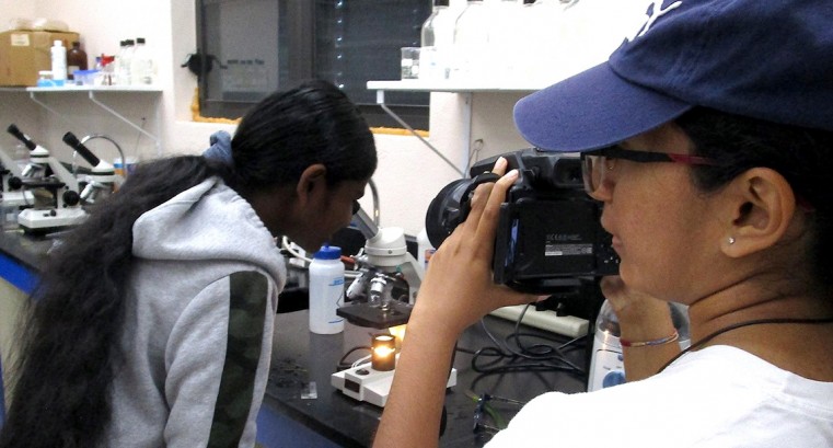 Ranger Dinara Perera videotapes Adriana Perera at the microscope - taping the activities for a future step-by-step how to run them in the classroom