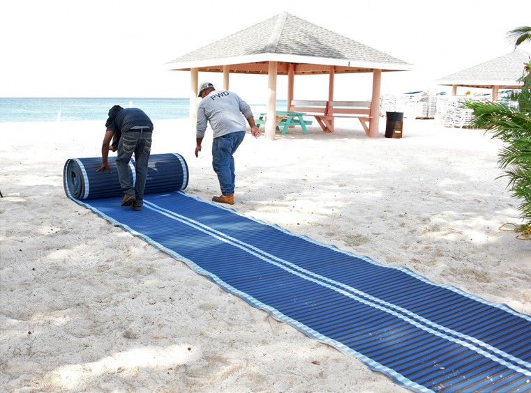 Members of the PWD team install the mobi-mat at the Seven Mile Beach