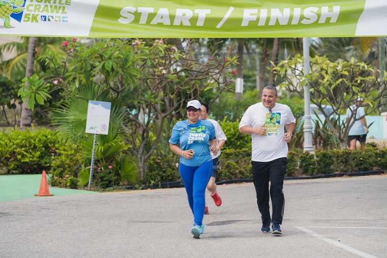 Corrine Ebanks and Deputy Governor Franz Manderson cross the finish line in the Turtle Crawl 5k