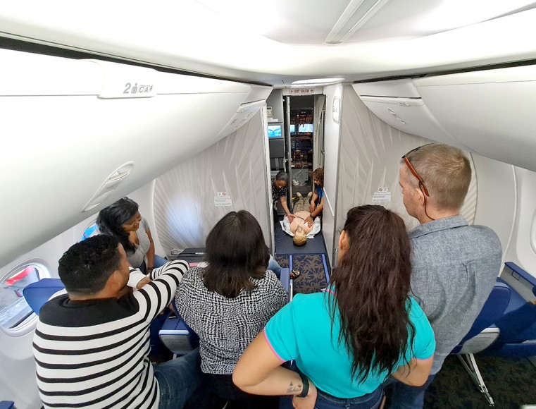 Cayman Airways Cabin Crew Members look on during a training session aboard one of the airline’s Boeing 737-8 aircraft, on how to operate an Automated External Defibrillator (AED) if a passenger is hav