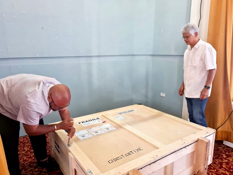 Minister for Culture and Heritage, Hon. Bernie Bush takes his turn in helping uncrate three Miss Lassie paintings last seen in Cayman more than 20 years ago. He is watched by the Cayman National Cultural Foundation’s Artistic Director Henry Muttoo