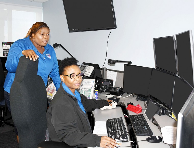 Department of Public Safety Communications Acting Assistant Director Ms Chelsea Blake (standing) talks with Communications Supervisor Ms Naddine Davis