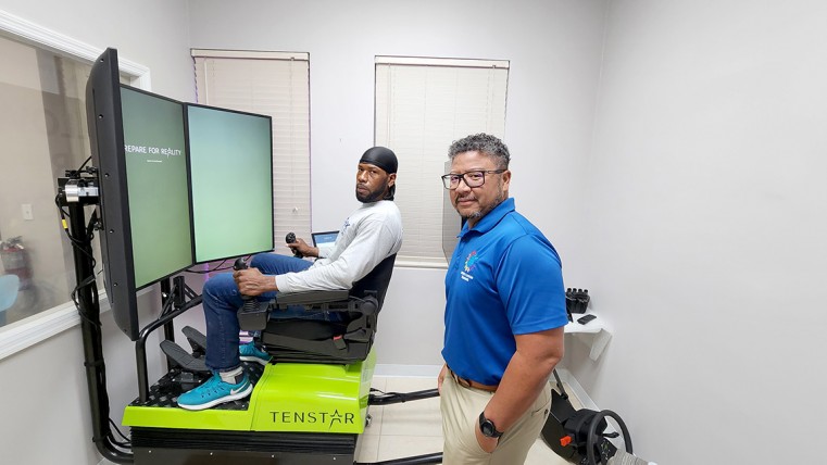 (L-R) Chris Myles sits in the simulator next to Chief Operating Officer and Instructor Mr. Sean Glidden.