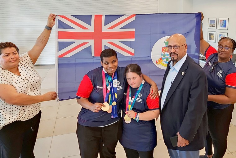 Sports and Culture Minister, the Honourable Berne Bush stands with two Special Olympic Athletes upon their return from competing at the Special Olympics World Games.
