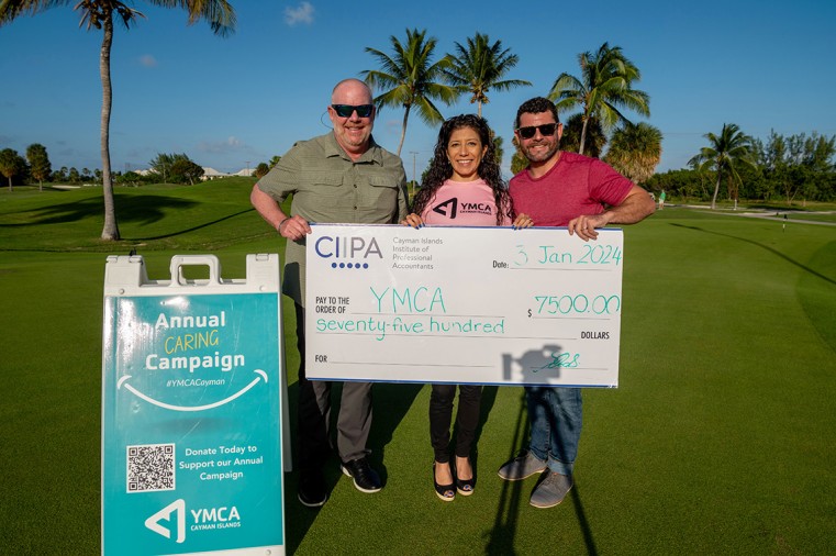 CIIPA Communications and Production Manager Kevin Morales, right, presents a donation cheque to YMCA of the Cayman Islands CEO Jeff Peterson, left, and Director of Philanthropy & Community Engagement