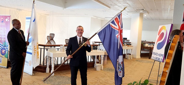 Rotarian Wil Pineau stands with the Caymanian flag at the opening ceremony for the District 7020 Create Hope 2024 Presidents Elect Training Seminar (PETS) and Conference on May 1st.