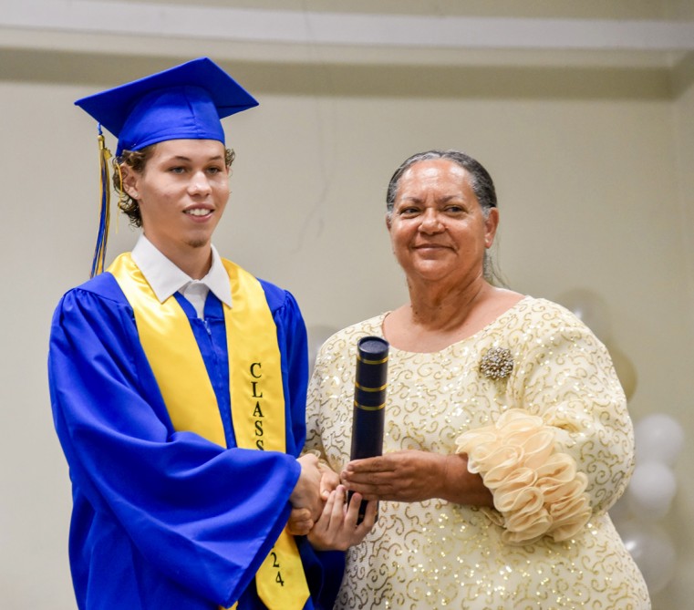 Premier and Minister for Education Honourable Juliana O’Connor-Connolly presents an award to honours graduate Sean-Lucas Martinez.