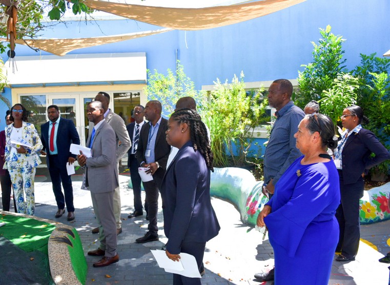 The Hon. Juliana O’Connor-Connolly (r) and members of the visiting party listen intently to Ms. Deniece Williams (Acting Principal, the Lighthouse School) during a tour of the school’s sensory garden.