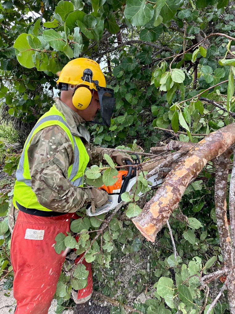 Cayman Islands Regiment Officer clearing fallen tree from roadway. Photo credit: CI Regiment