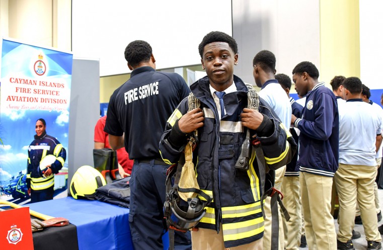A CHHS students tries on firefighter gear at the Cayman Islands Fire Service (CIFS) booth.