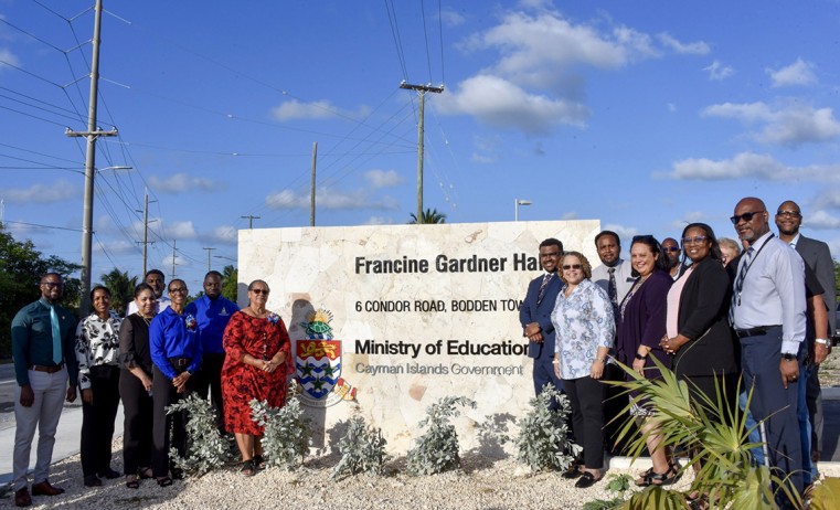 Hon. Juliana O’Connor Connolly, joined by Ministry and Department of Education Services staff, stands in front of the newly unveiled sign.